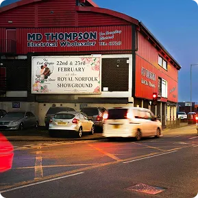 A roadside billboard on the side of a building in view of a busy road
