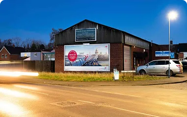 A Roadside Billboard on the side of a building with traffic passing by